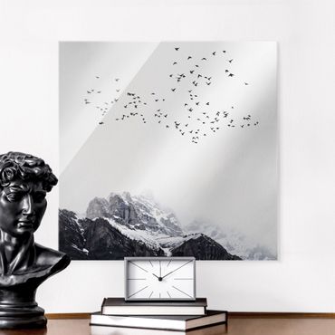 Glasbild - Vogelschwarm vor Bergen Schwarz Weiß - Quadrat 1:1